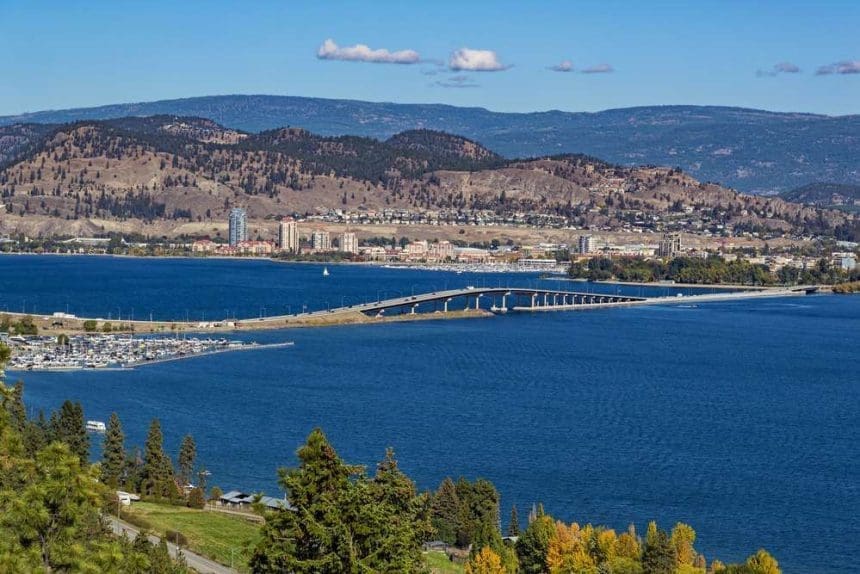 A view of the bridge over Okanagan Lake between West Kelowna and Kelowna Brititsh Columbia Canada with a view of the Kelowna skyline and a marina in the foreground.