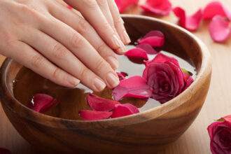 A woman's hands go into a bowl of milk with roses on top, representing Spas in Vancouver.