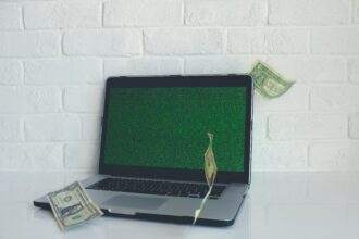 A laptop and a few dollar notes scattered on it. The concept of how to make money online in Canada.