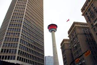 A low-angle shot of Calgary Tower among the high-rise buildings.
