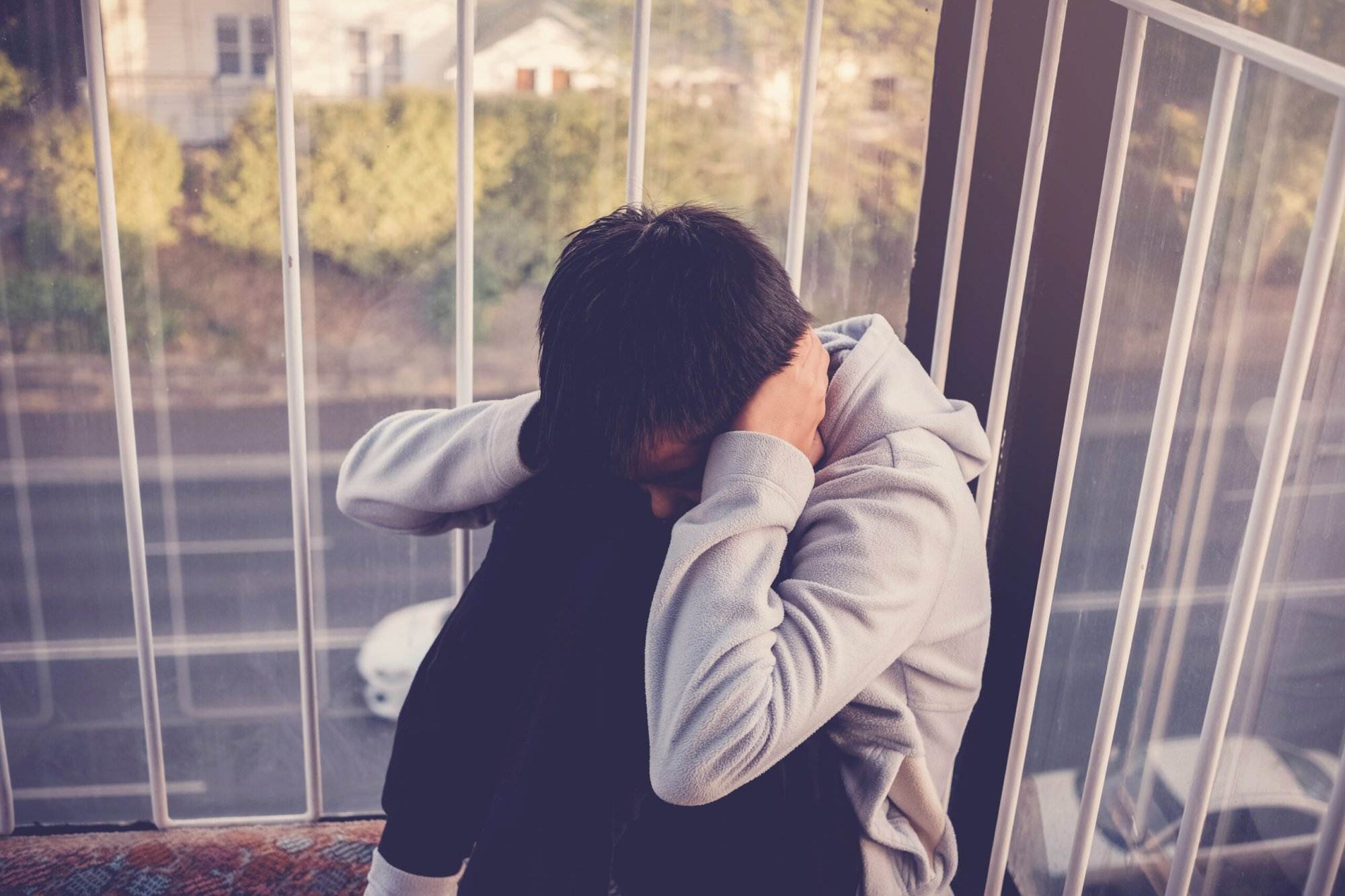 A depressed young teenage boy, with Autism, covering his ears. The Concept of Autism Spectrum Disorder.