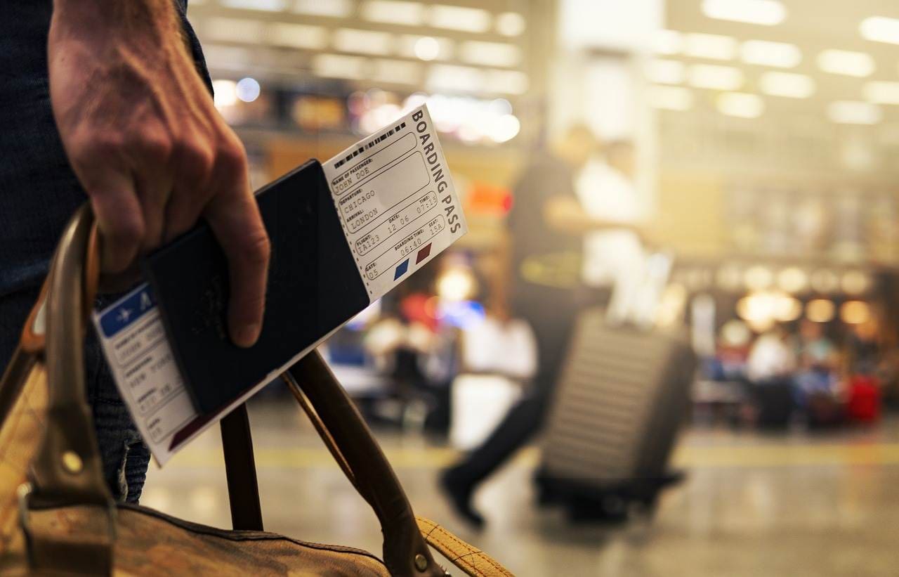 A man carrying his passport and boarding pass to the airport.