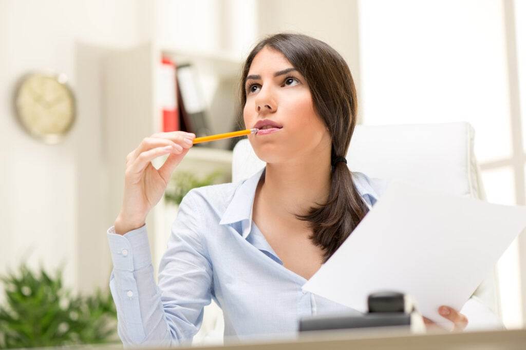 A woman looking in the upward direction while thinking in the office.
