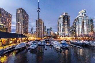 A view of cruises beside the dock with high-rise buildings in the background during the evening time in Toronto.