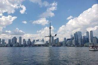 A view of the entertainment district of Toronto with high-rise buildings in the background and a waterbody in the front.