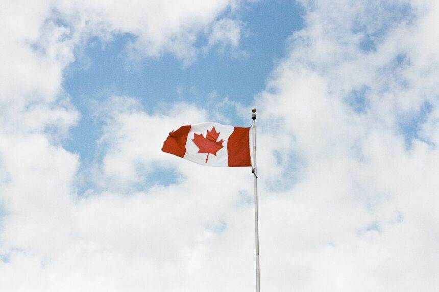 A Canadian flag is high up in the sky.
