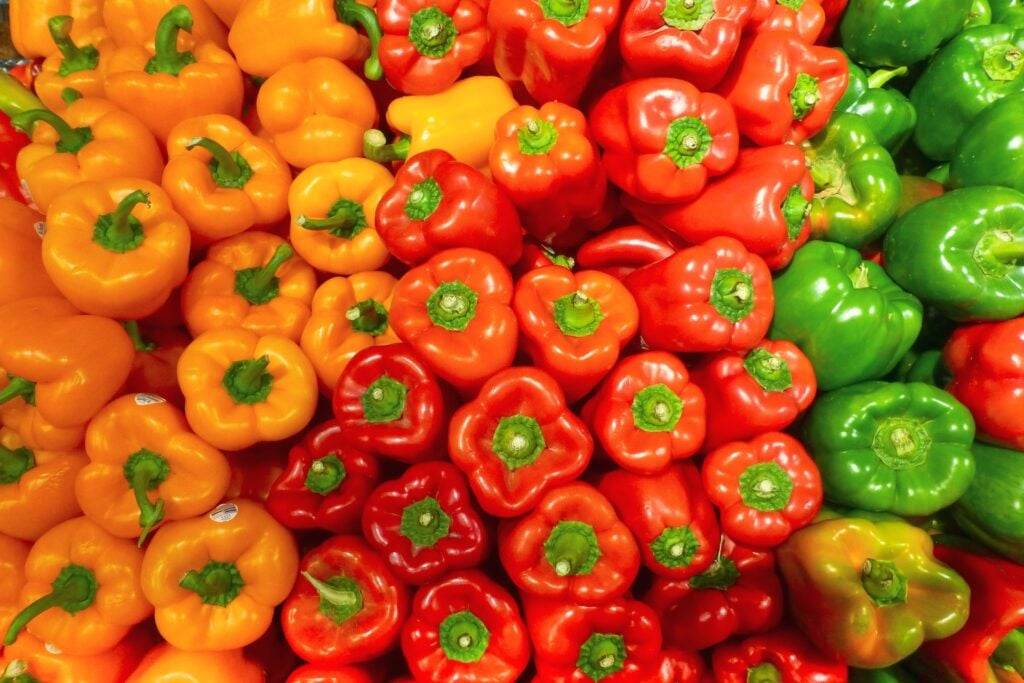 Display of orange, red and green bell peppers in a farmers market in Vancouver.