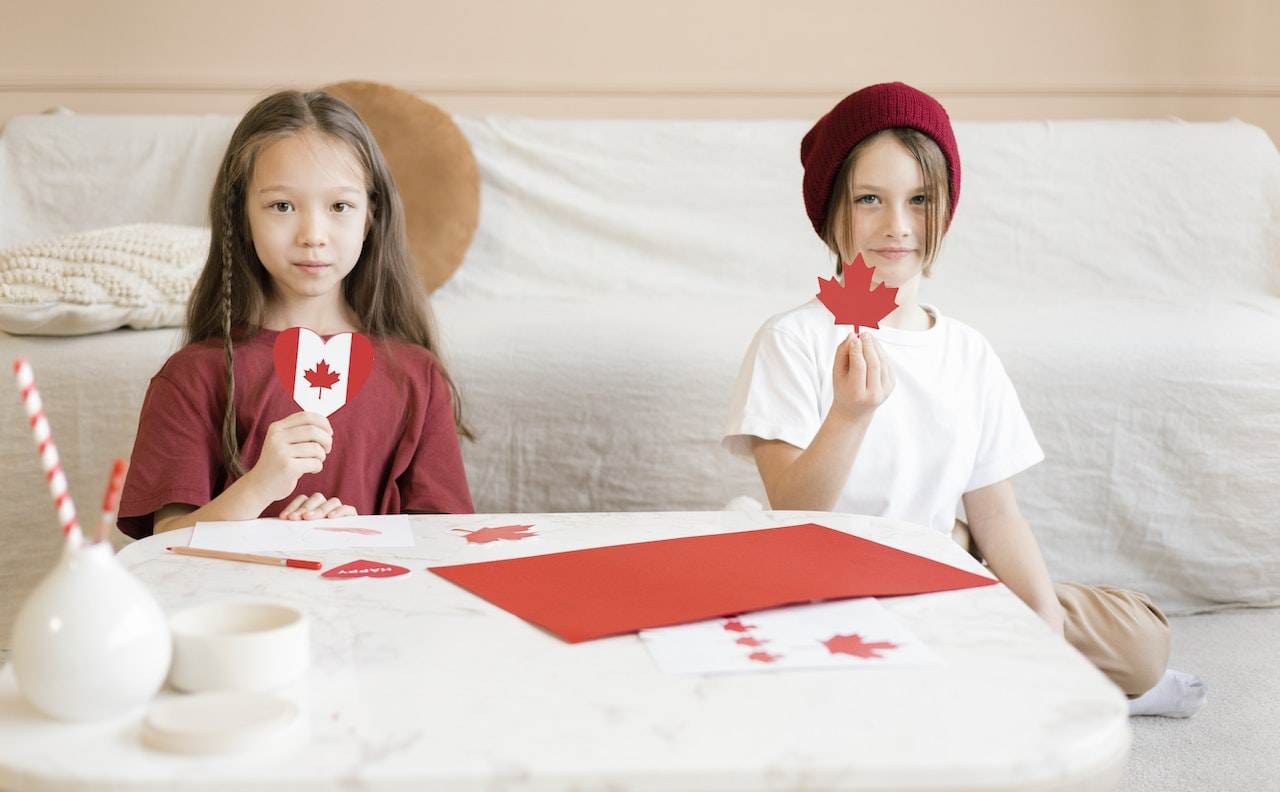 Kids making the stickers of the Canadian flag.