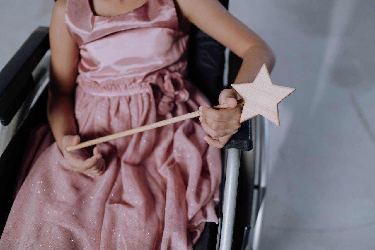 A child with a fairy costume sitting in a wheelchair.