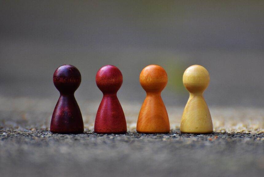 Four wooden pawn figures in brown, red, orange and yellow colour.