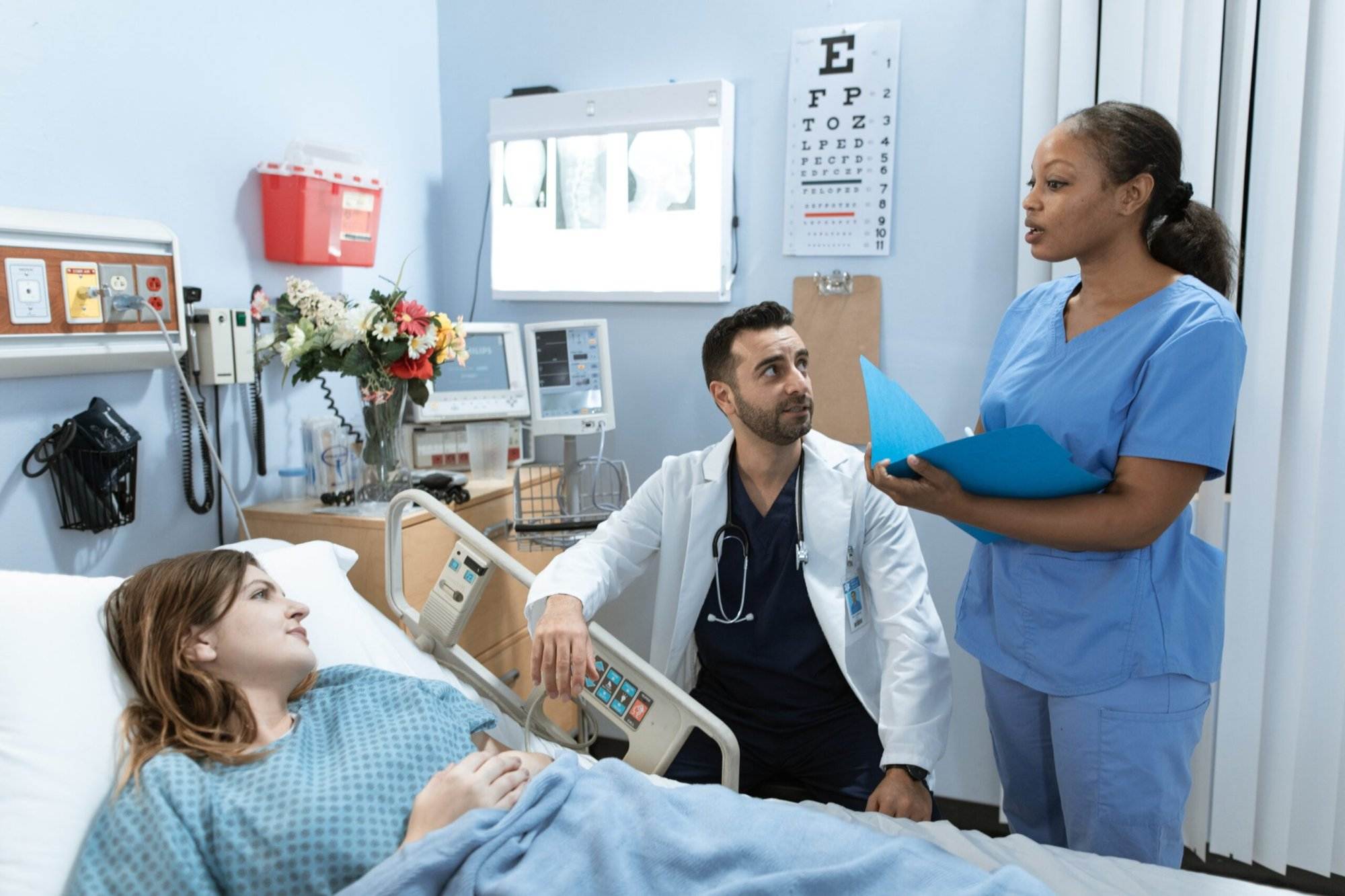 A nurse in a hospital room giving advice to the patient in front of her doctor as well.