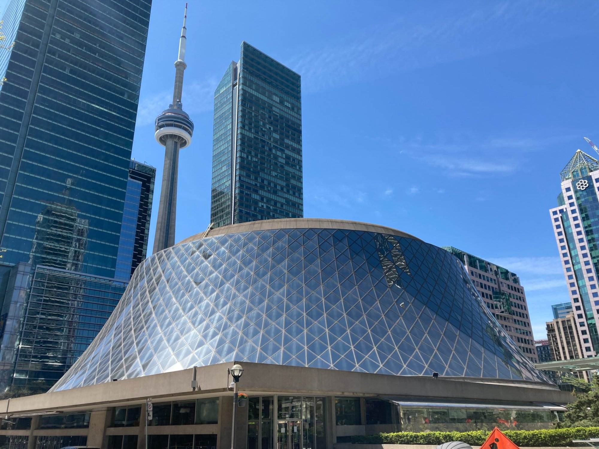A very large building of Roy Thomson Hall with a very tall tower in the background.
