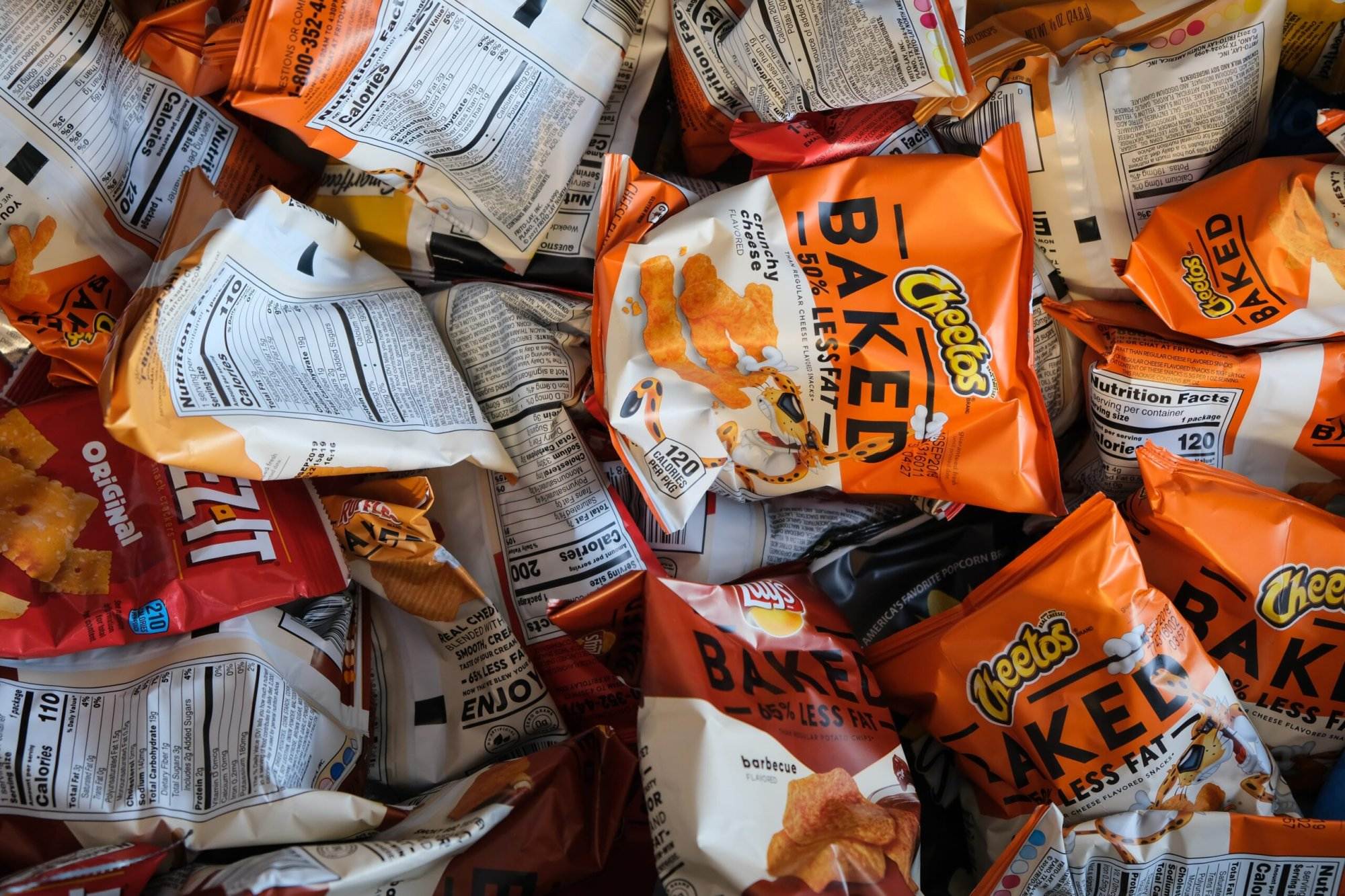 A many orange-colored packets of junk snacks.