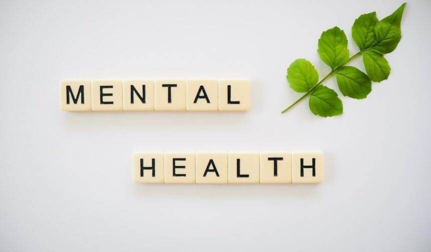 Mental health is spelled out with wooden scrabbles on a white background.