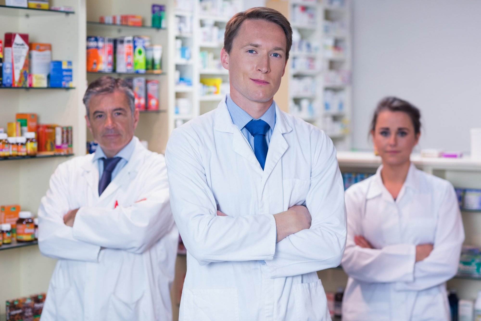 Smiling pharmacy team standing with arms folded in the pharmacy