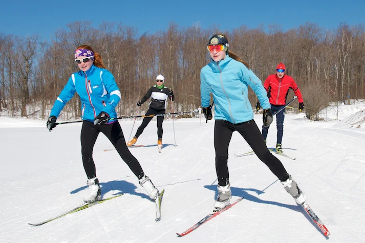 A group of people skiing on the snow on a sunny day.
