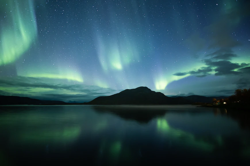 A green light in the sky over a waterbody during the nighttime.