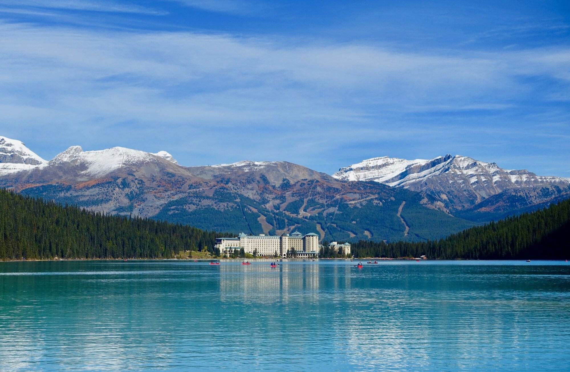 A view of a hotel at a far distance beside the Lake Louise.