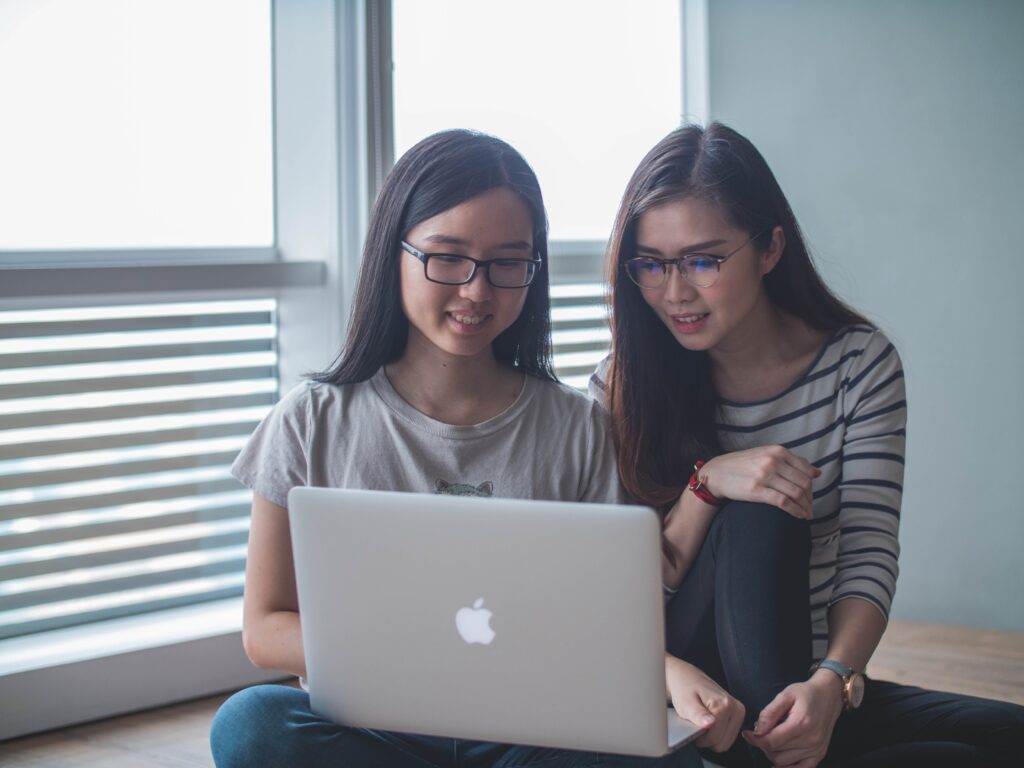 Two ladies work on a laptop.