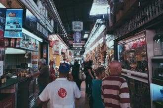People walk on the passage between two shelves in a store to see things to buy