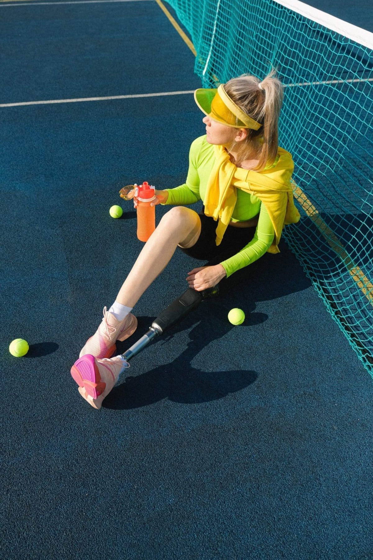A tennis player sitting on the floor of the lawn.