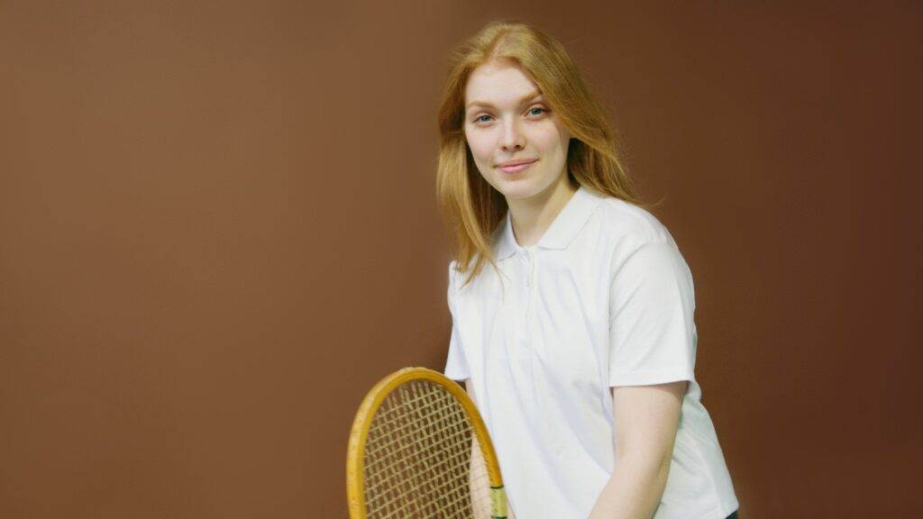 A woman with golden hair wearing a solid white coloured t-shirt for a Tennis outfit.