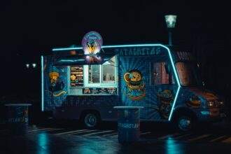 a photo of a food truck neon lights clicked in the night with