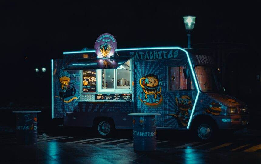 a photo of a food truck neon lights clicked in the night with