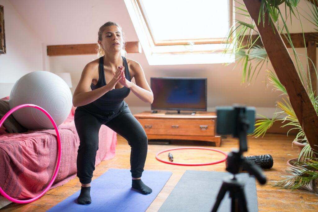 A woman recording herself while doing exercise.