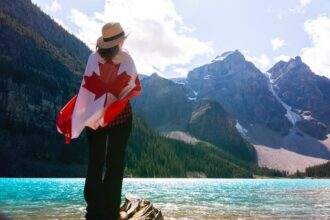 A woman standing with a Canadian flag beside Lake Louise.