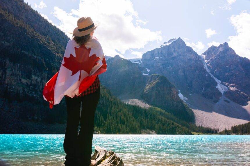 A woman standing with a Canadian flag beside Lake Louise.