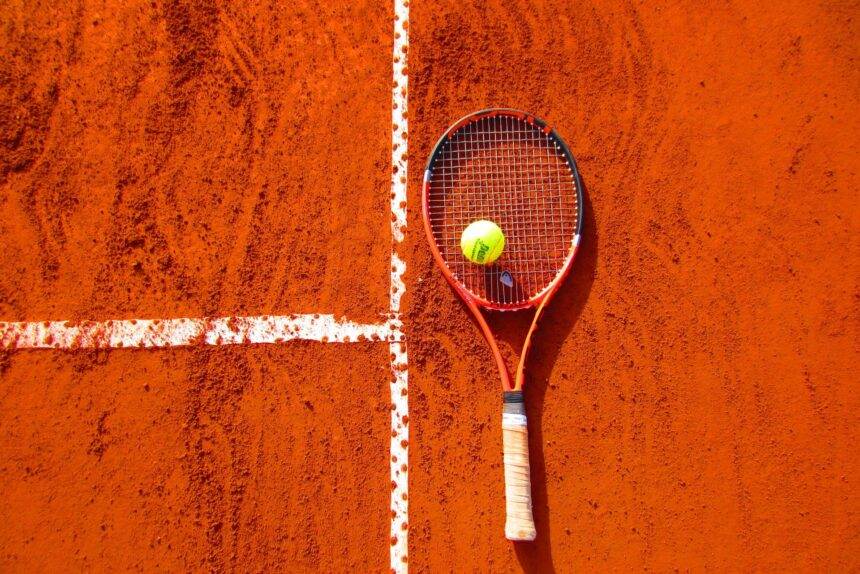 A top view of a tennis racket and a ball kept on the tennis ground.