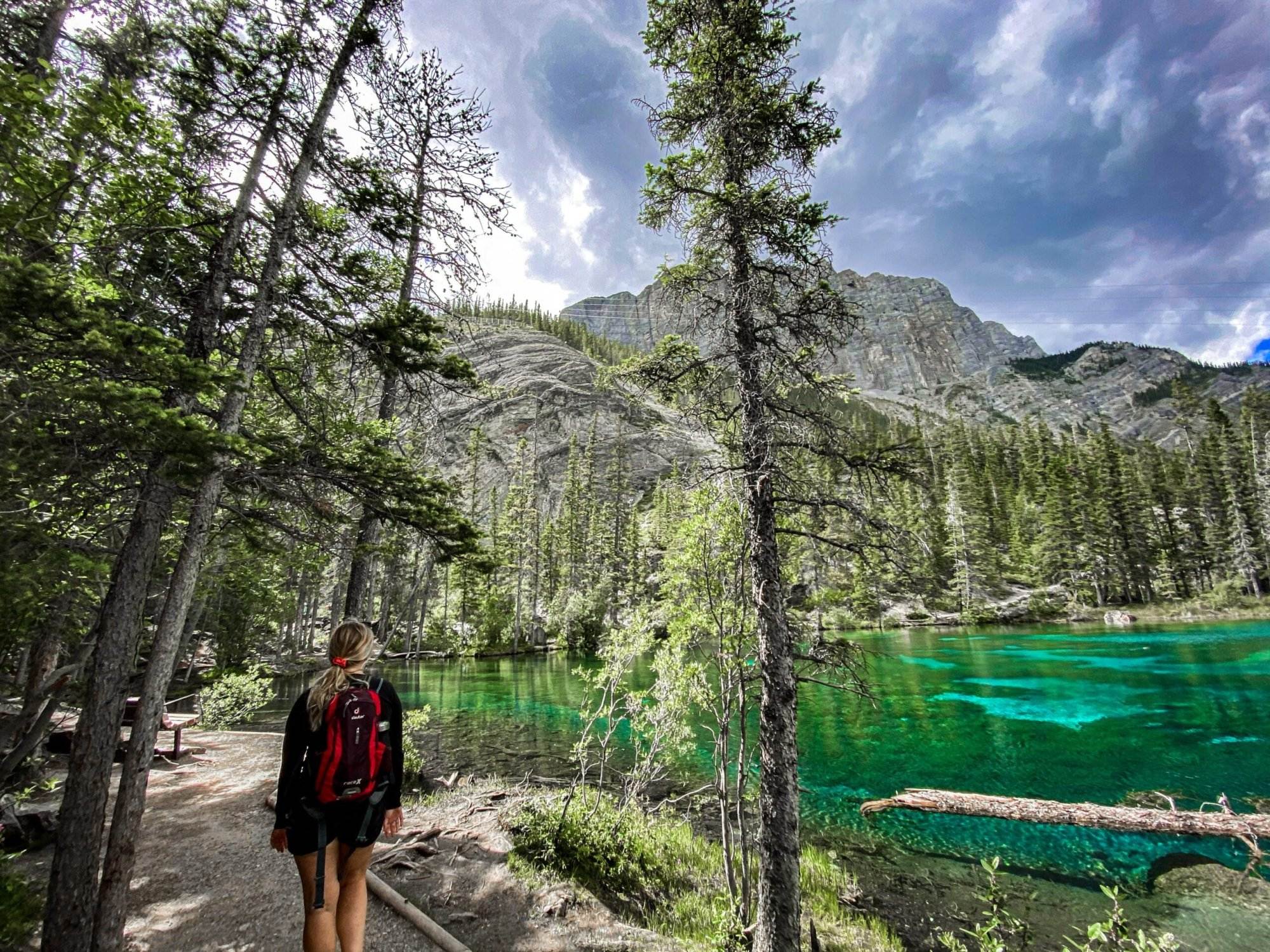 A woman hiking along the trail beside the Grassi Lakes.