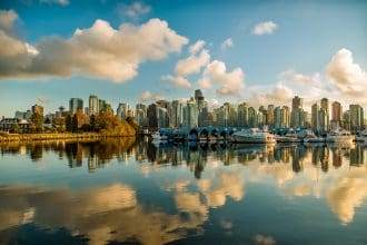 A scenic view of Vancouver with the high-rise buildings and a waterbody alongside.