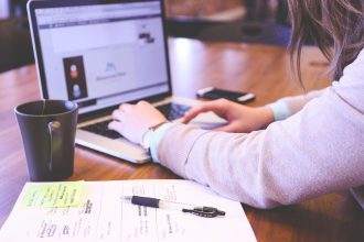A person working on their laptop with a coffee mug on the table.