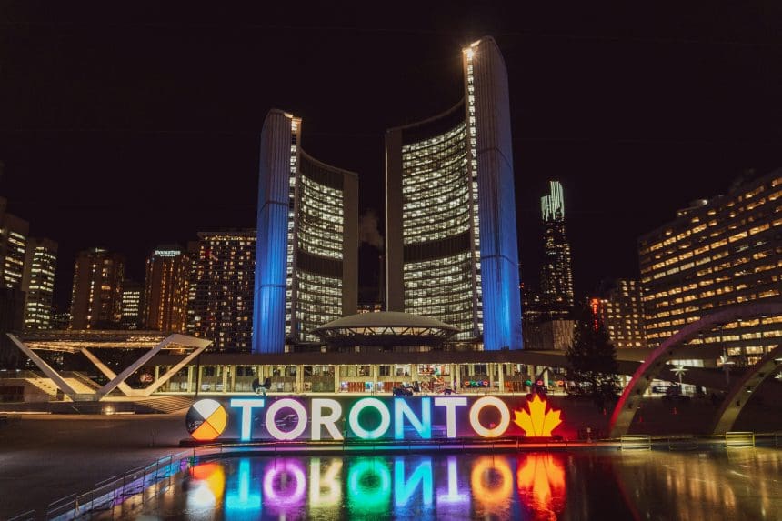Toronto cityscape at night with illuminated buildings and reflections.