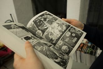 Close-up of hands holding an open manga book.