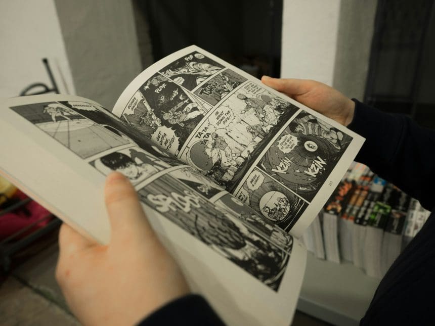 Close-up of hands holding an open manga book.