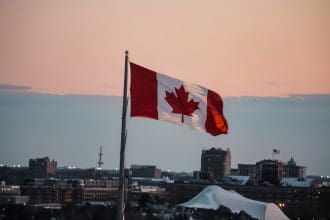 Canadian flag over city skyline at dusk