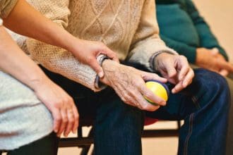 Young person providing care to elderly individual holding a ball.