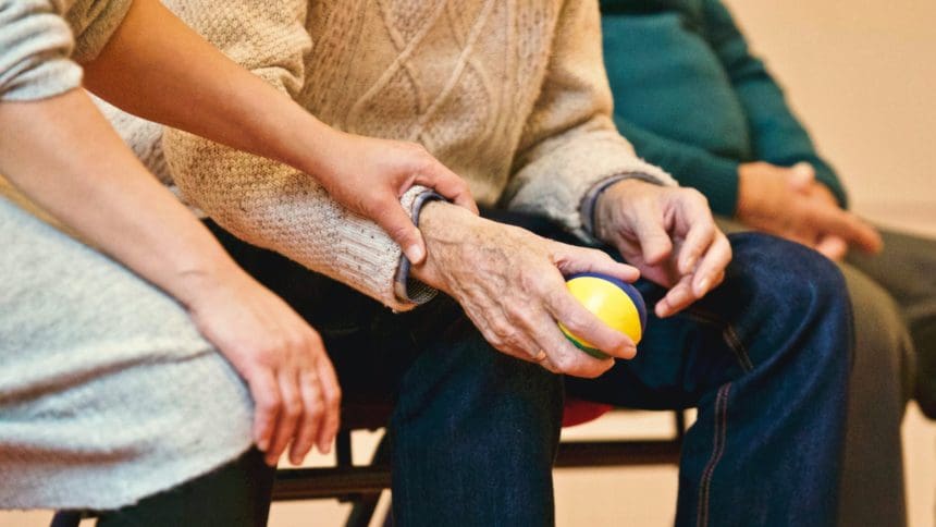 Young person providing care to elderly individual holding a ball.