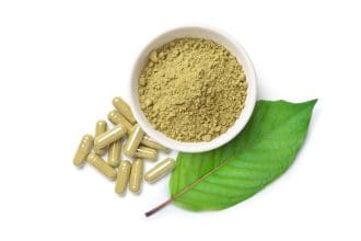 Kratom capsules, powder, and leaf isolated on white background.
