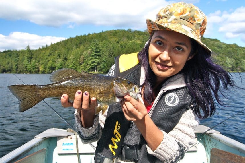 Woman holding a fish on a boat during a sunny day.