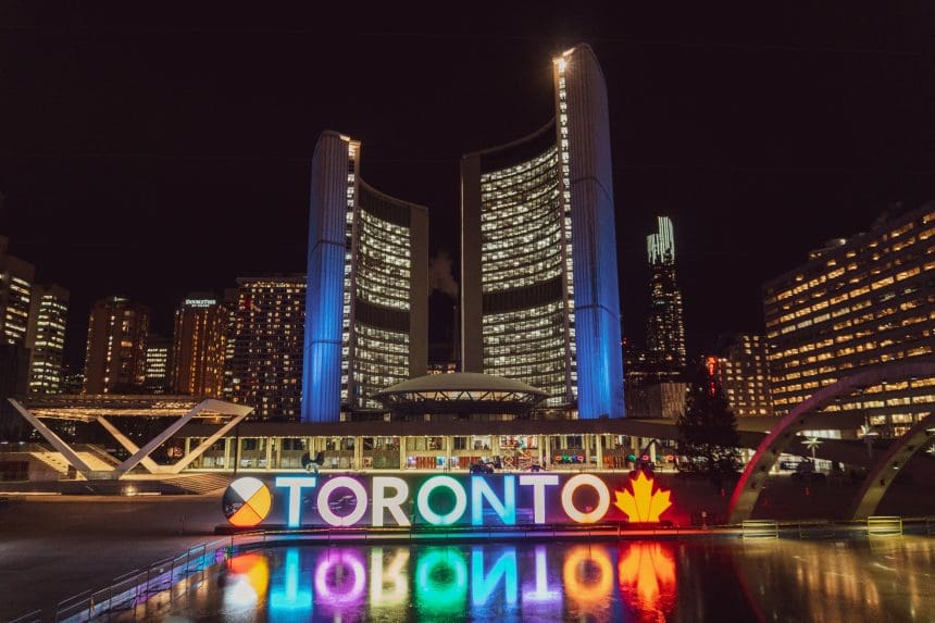 Toronto cityscape at night with illuminated sign and reflections.
