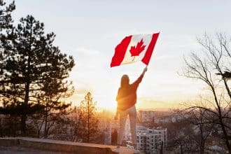Woman holding Canadian flag at sunset