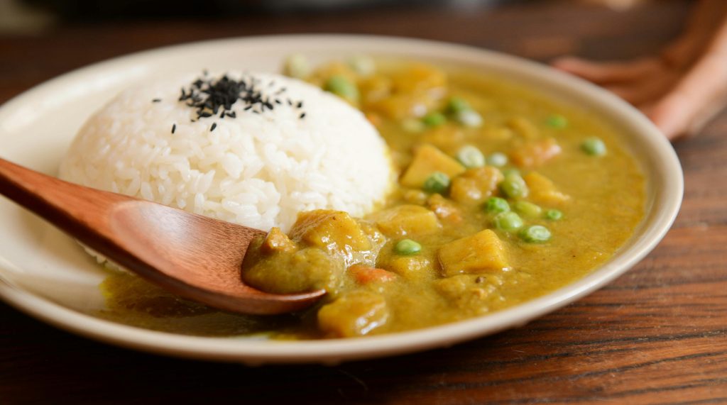 a serving of curry along side with rice.